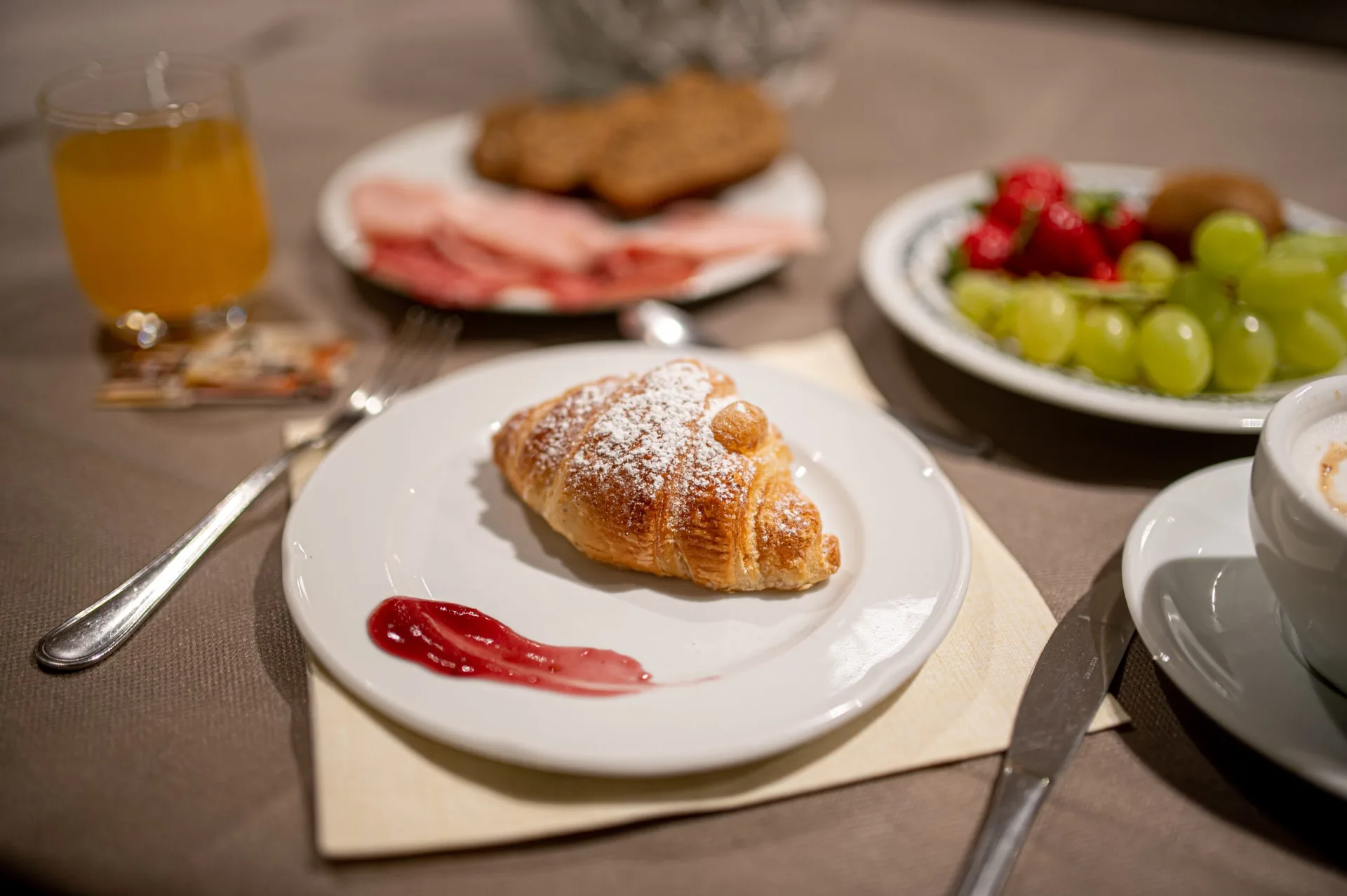 Colazione con cornetto, succo d'arancia, frutta fresca e cappuccino