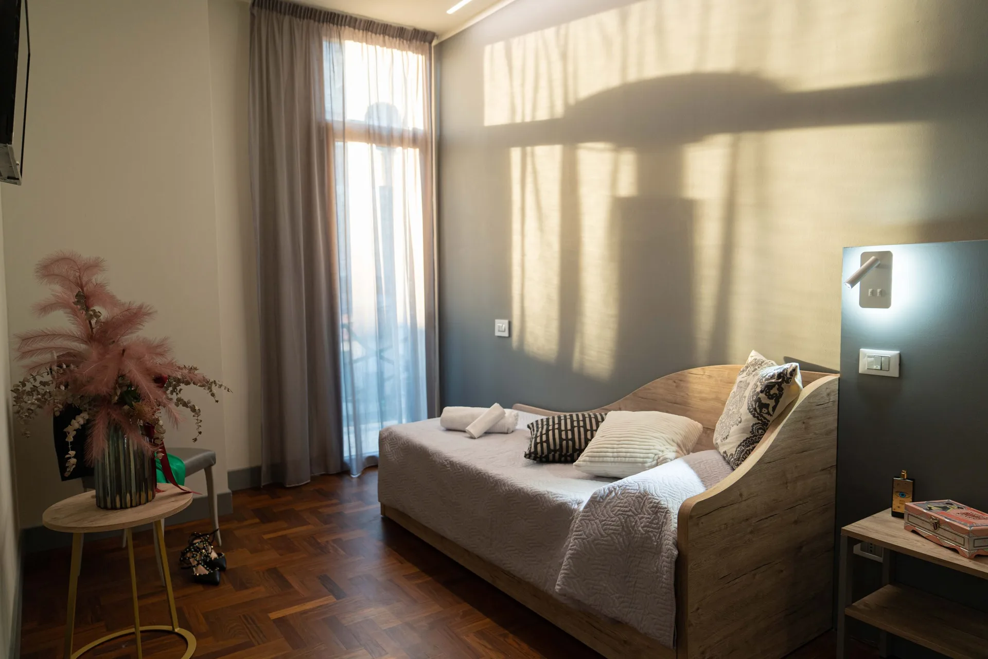Camera luminosa con divano letto in legno, ampia finestra e parquet