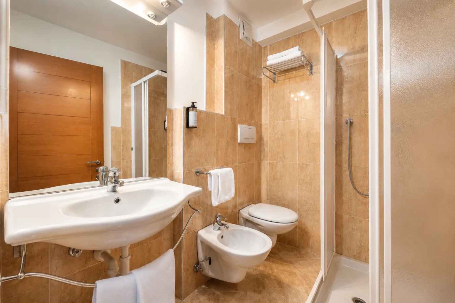 Bagno con doccia, lavabo, bidet e piastrelle beige