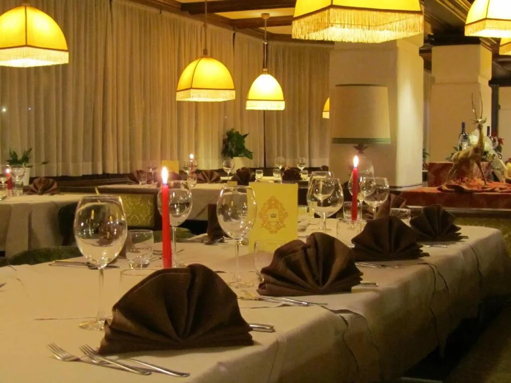 Tavolo del ristorante con calici, candele rosse e tovaglioli marroni piegati a ventaglio
