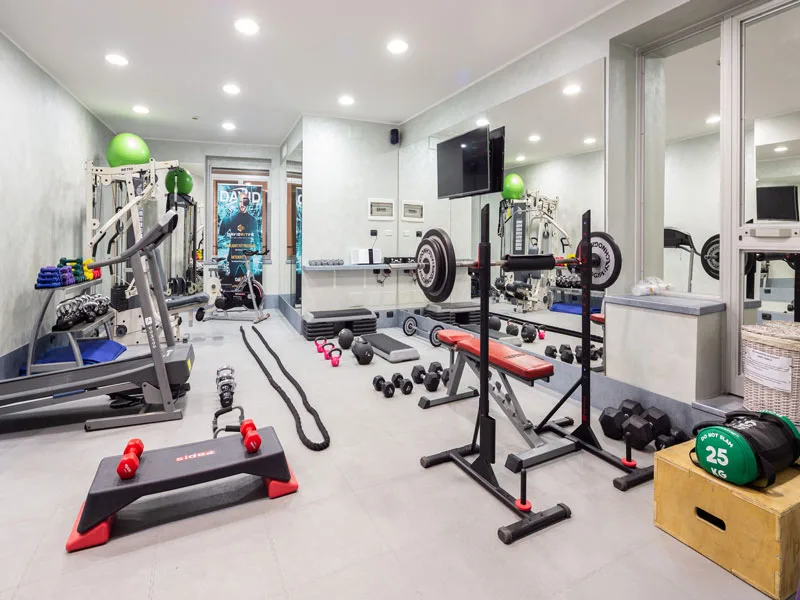 Palestra attrezzata con pesi, tapis roulant, panca e specchi a parete