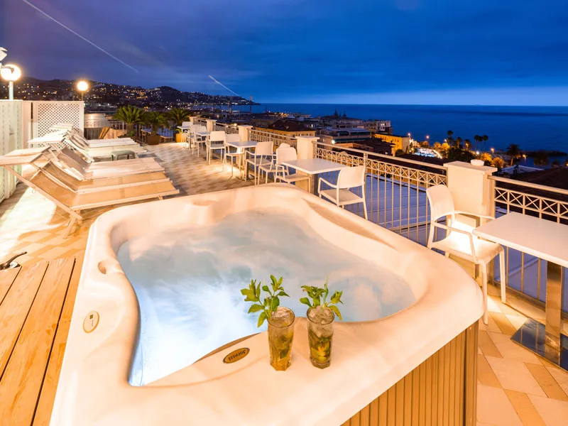 Terrazza panoramica con vasca idromassaggio, vista sul mare al tramonto e cocktail