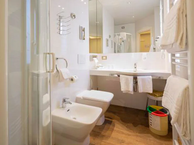 Bagno con doccia, sanitari bianchi, lavabo e specchio ampio