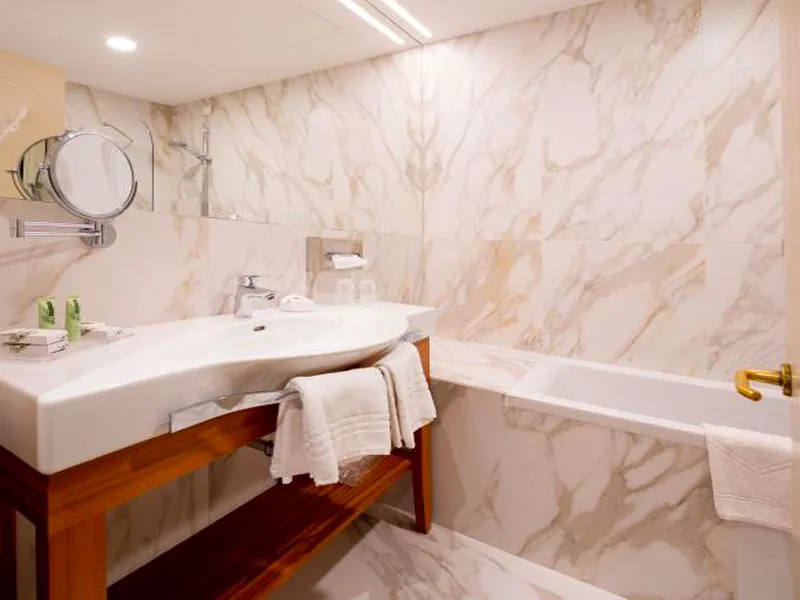 Bagno rivestito in marmo con lavabo, vasca e specchio ingranditore