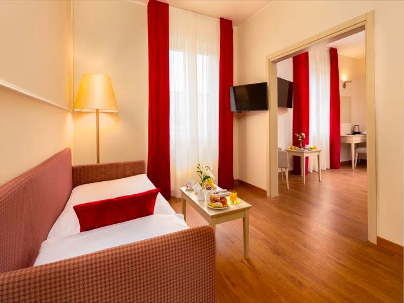 Suite con divano letto, tende rosse, TV e camera comunicante