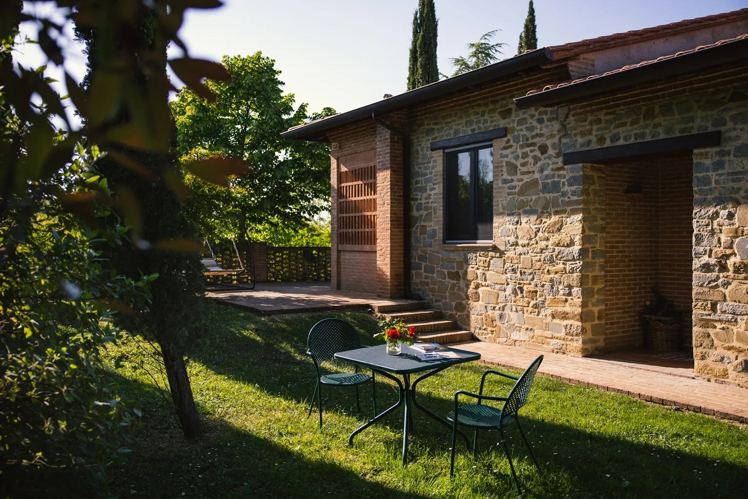 Casetta in pietra e mattoni con tavolo da giardino e terrazza tra il verde