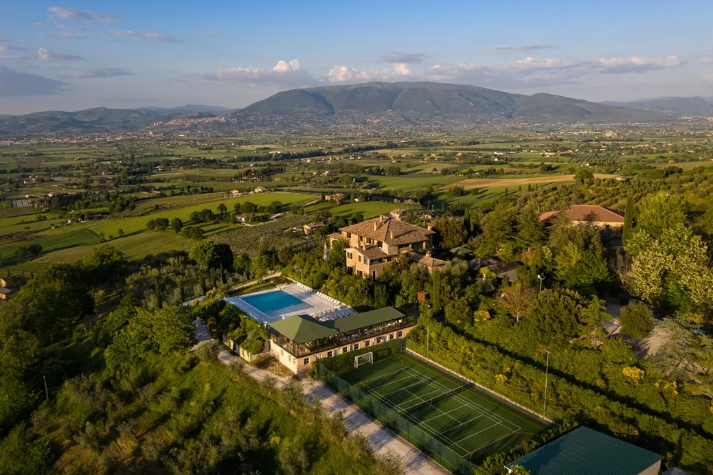 Vista aerea del complesso in campagna con piscina, campo da tennis e ampio panorama sulla vallata verde