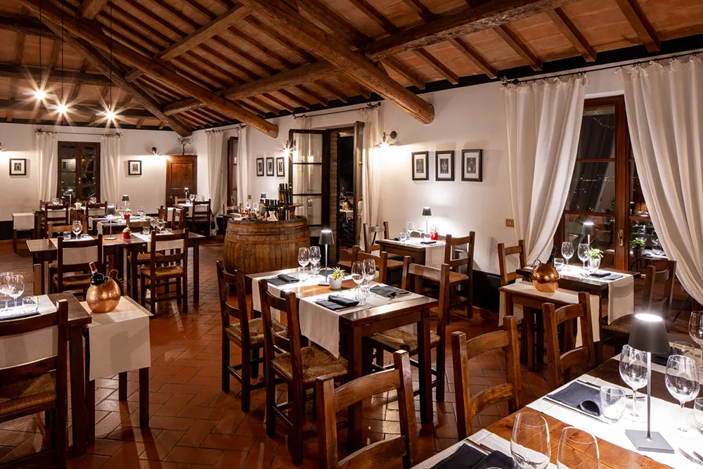 Ristorante con soffitto in travi di legno, tavoli apparecchiati e botte di vino centrale