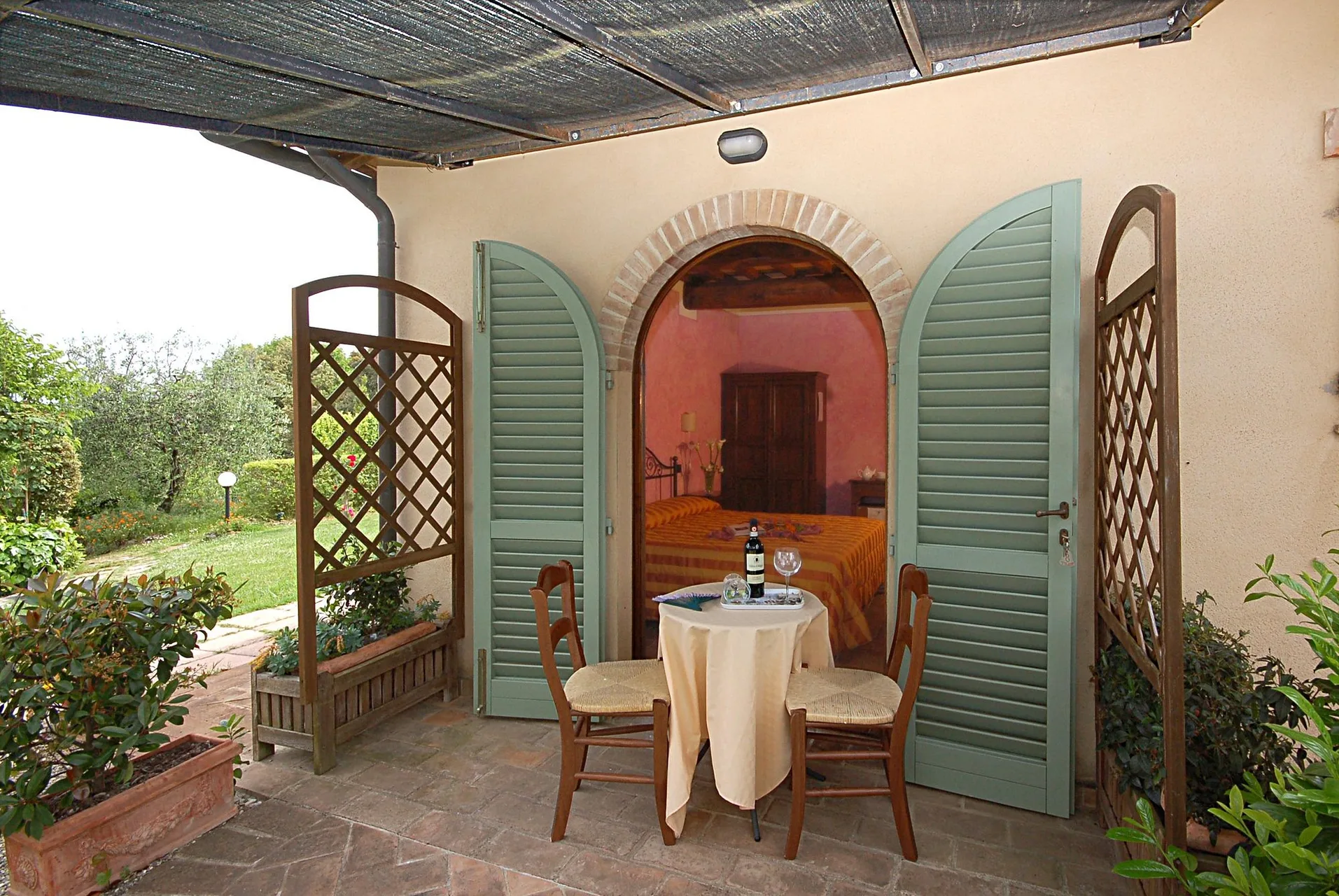 Terrazza privata con tavolino e vista sull'ingresso arcato di una camera dai toni rosa