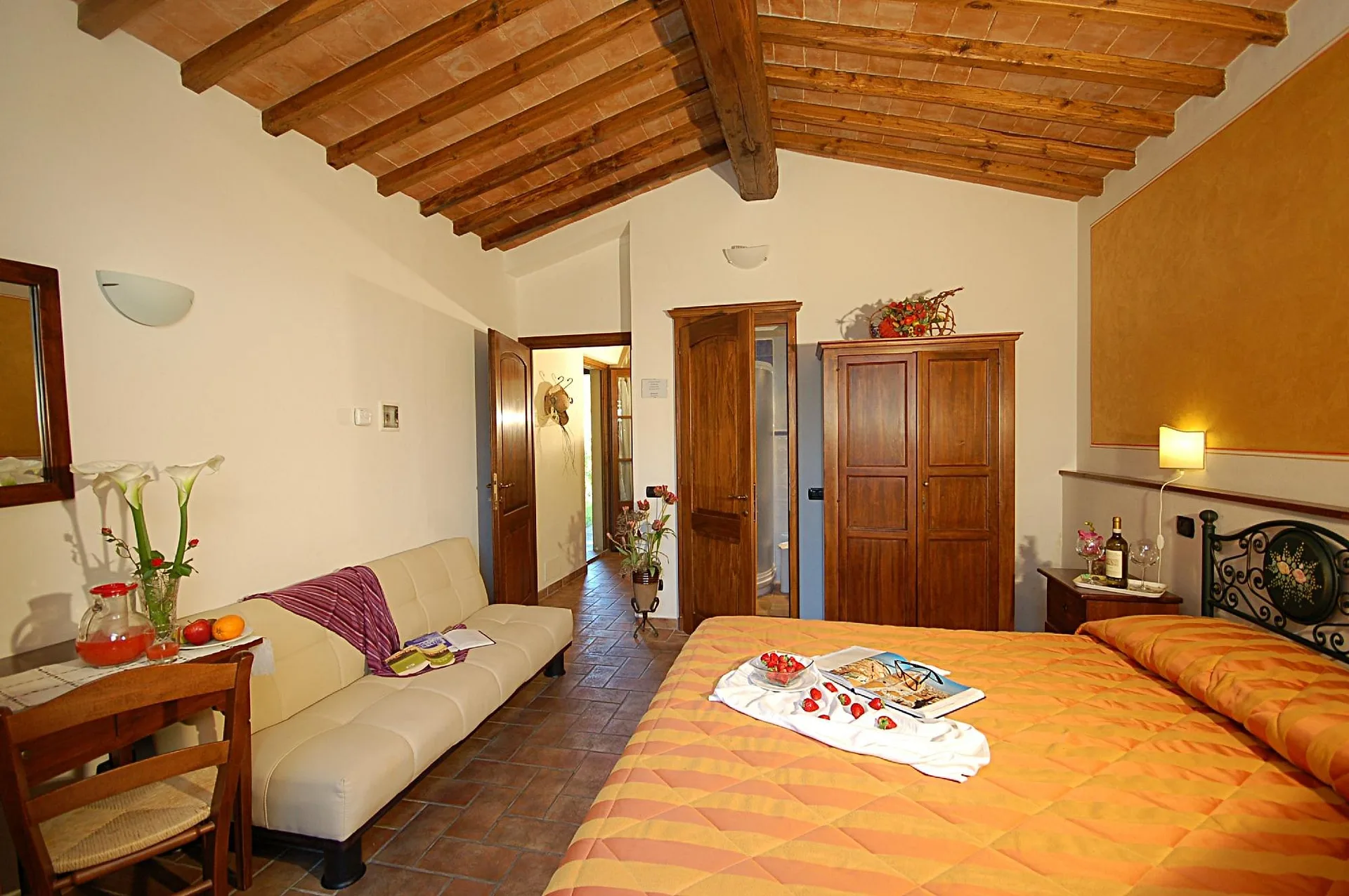 Camera con letto matrimoniale, divano e soffitto in legno con travi a vista