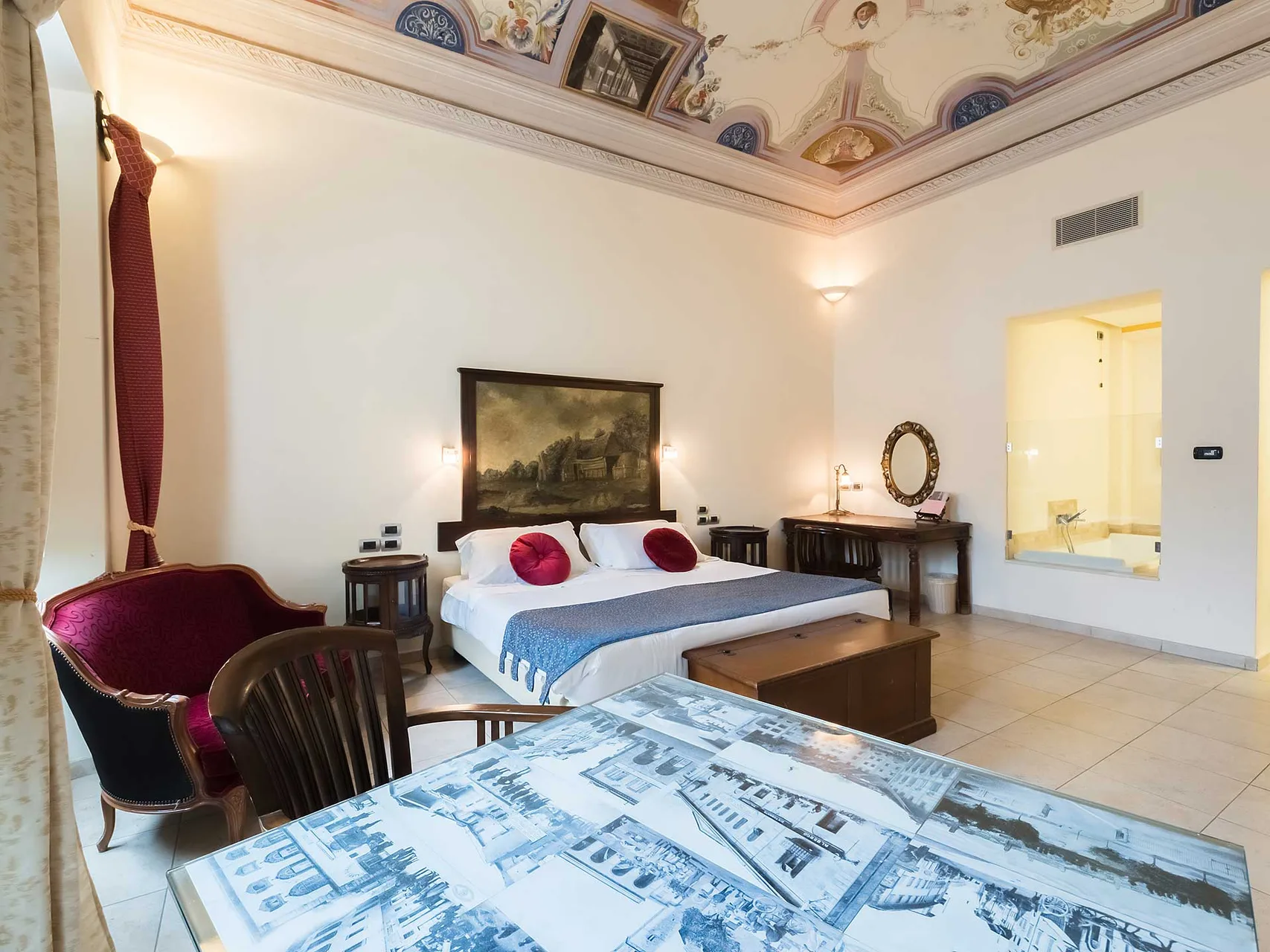 Suite di lusso con soffitto affrescato, letto matrimoniale, poltrona antica e vasca idromassaggio a vista