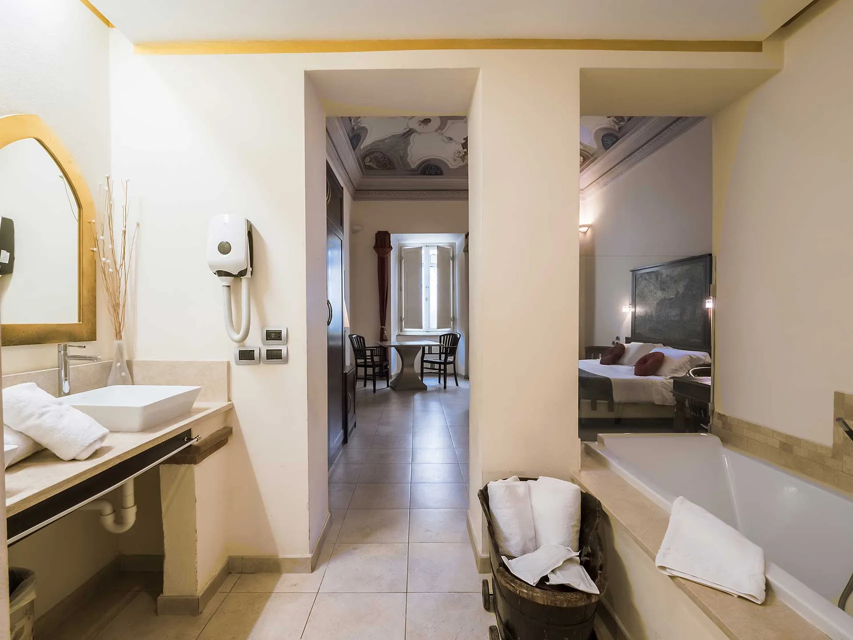 Bagno con lavabo, vasca e corridoio che collega alla camera con soffitto affrescato