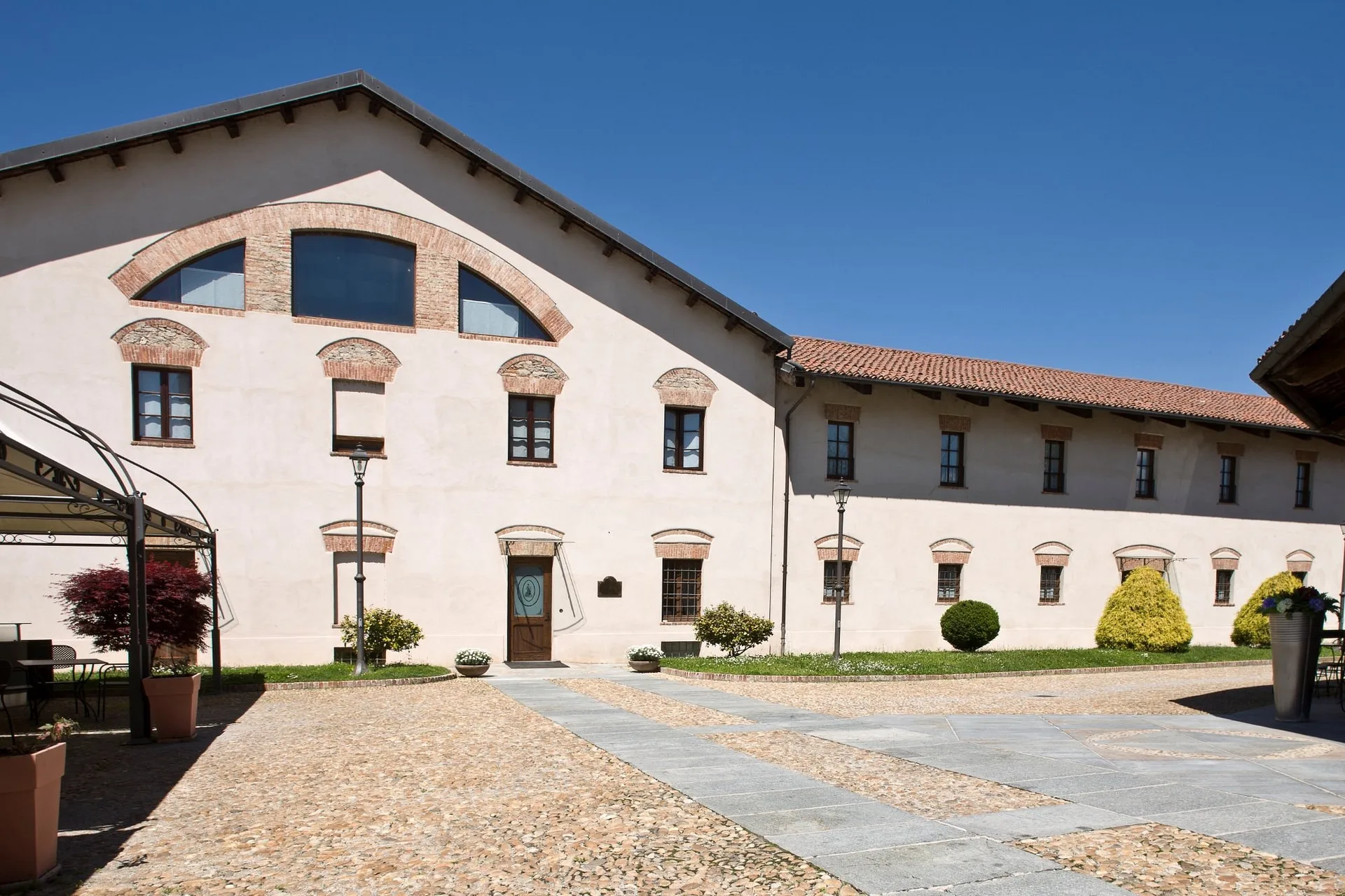 Corte interna storica con facciate intonacate chiare, dettagli in mattoni e pavimentazione a ciottoli