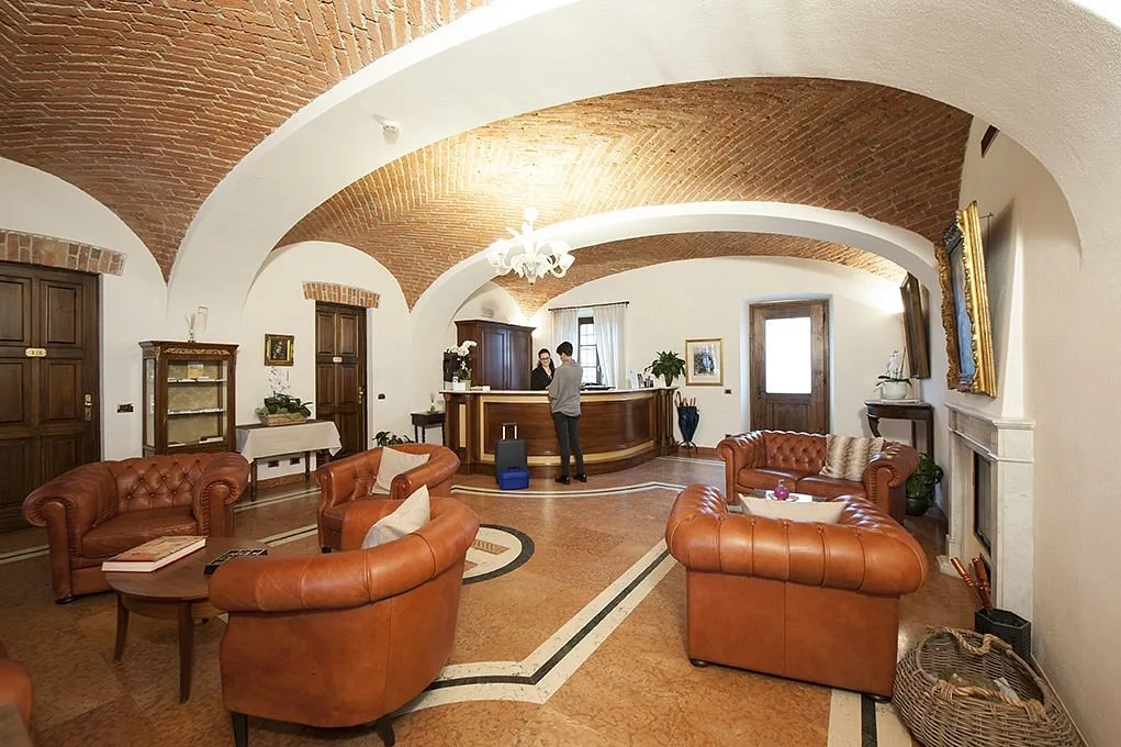 Hall dell'hotel con soffitto a volte in mattoni, poltrone e divani in pelle marrone e reception in legno
