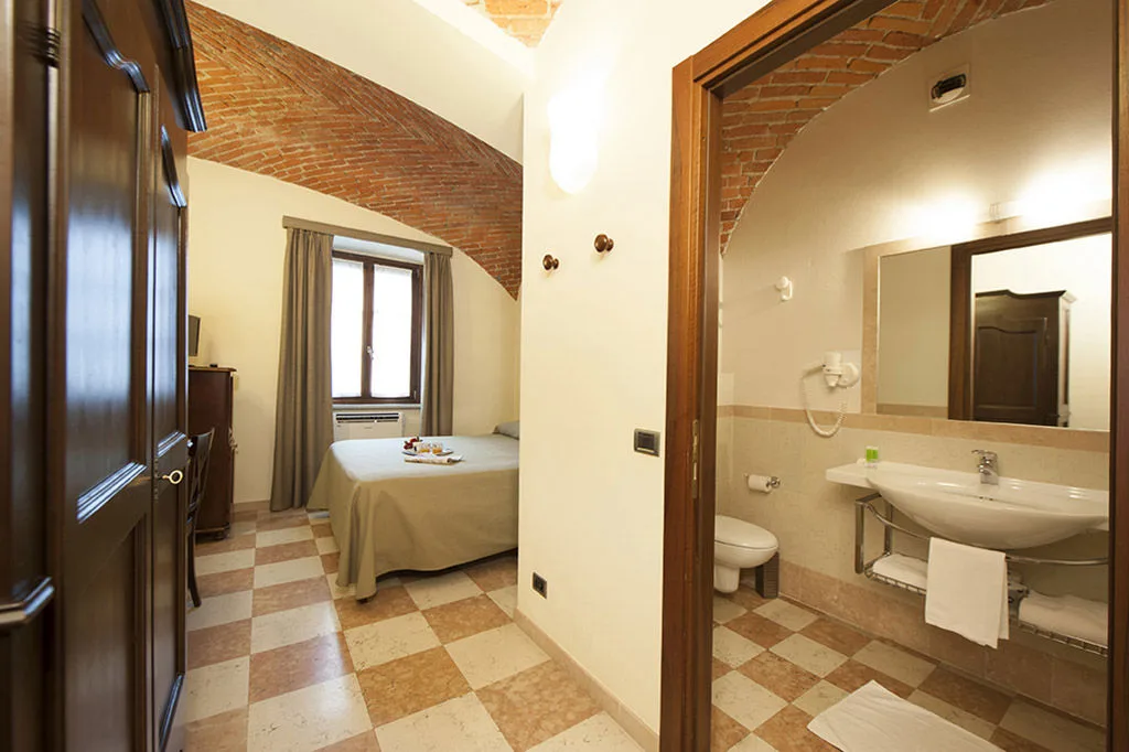 Camera con bagno en-suite, soffitto a volte in mattoni, letto e pavimento a scacchi