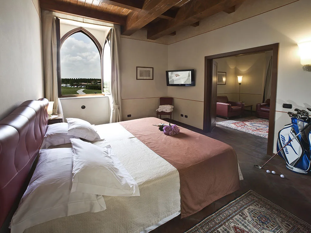 Suite con soffitto in legno, letto matrimoniale, finestra ad arco con vista e sala salotto attigua