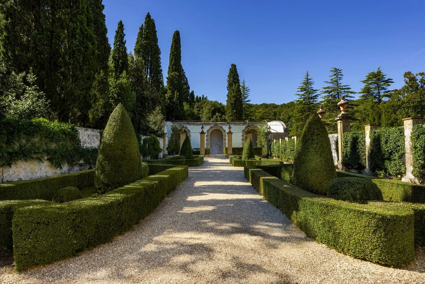 Giardino all'italiana con siepi geometriche, cipressi e viale in ghiaia