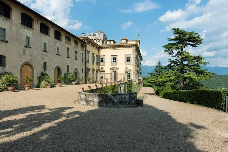 Cortile in ghiaia davanti alla facciata della villa storica con vista sulle montagne
