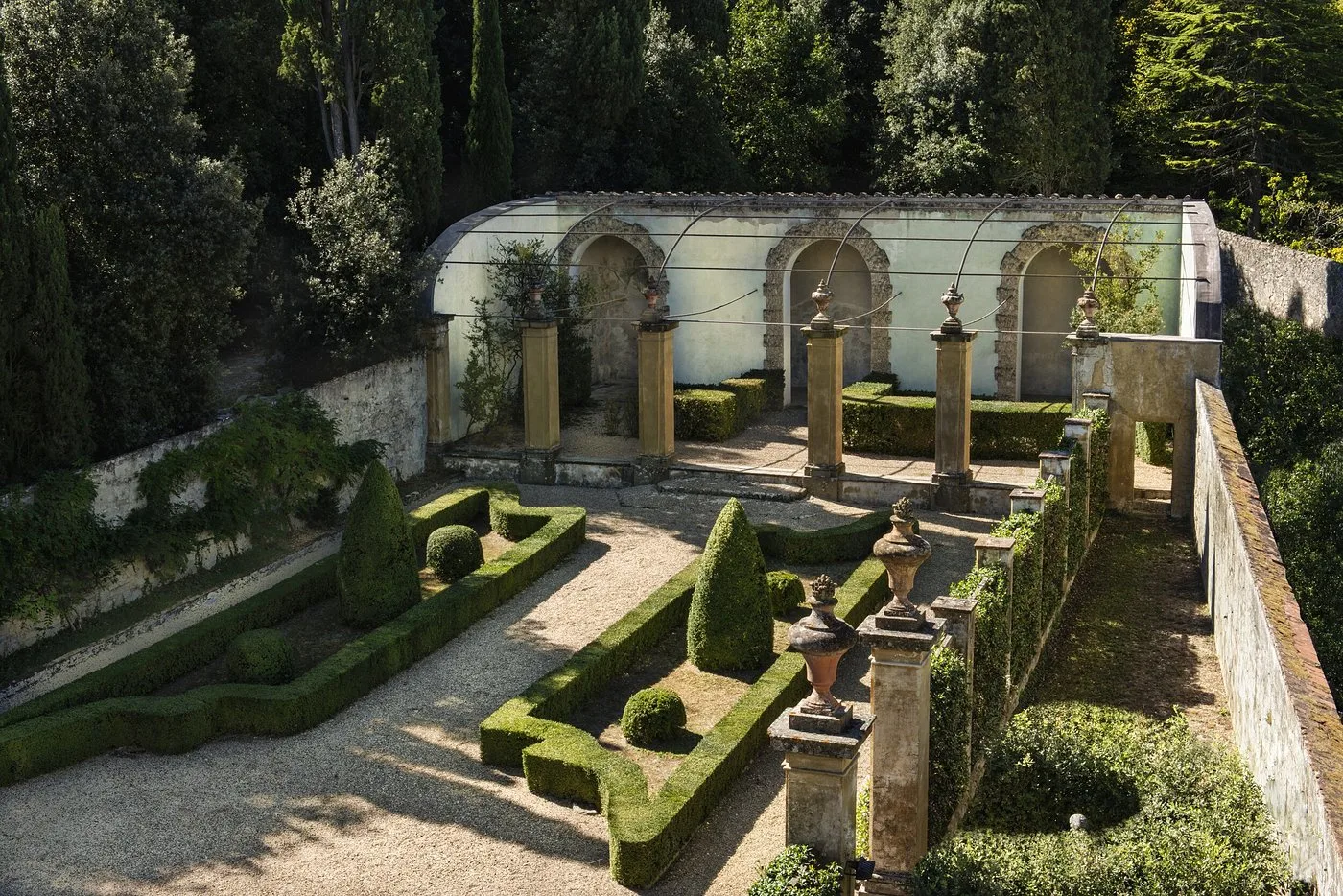Giardino all'italiana con loggiato antico, siepi geometriche e vasi in terracotta