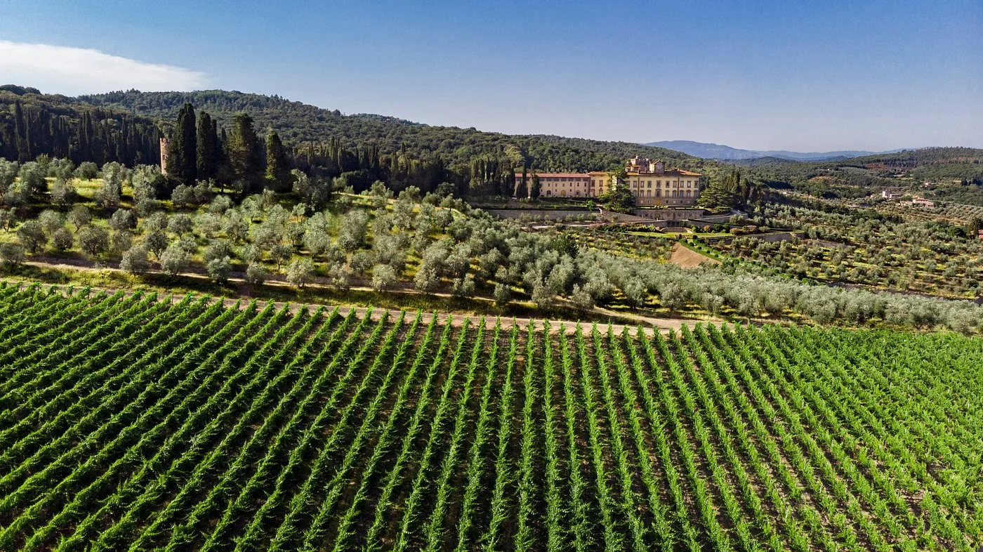 Veduta aerea di villa storica tra vigneti e uliveti sulle colline toscane