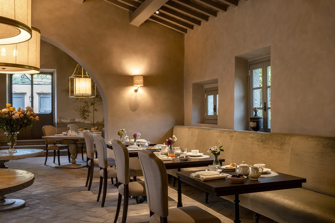 Sala colazione elegante con tavoli apparecchiati, fiori e soffitto a travi
