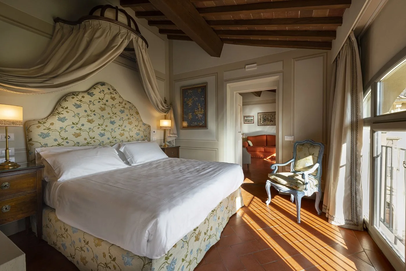 Suite con letto a baldacchino, testiera floreale e vista sul soggiorno adiacente