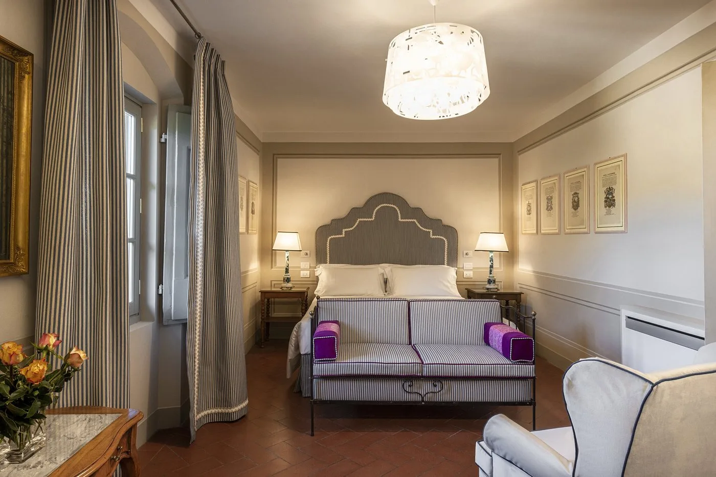 Camera classica con testiera a righe, divano e pareti decorate