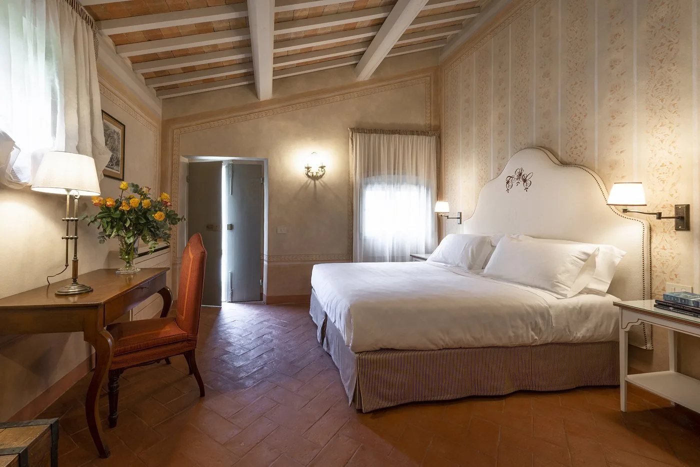 Camera da letto con pareti decorate, scrivania in legno e pavimento in cotto