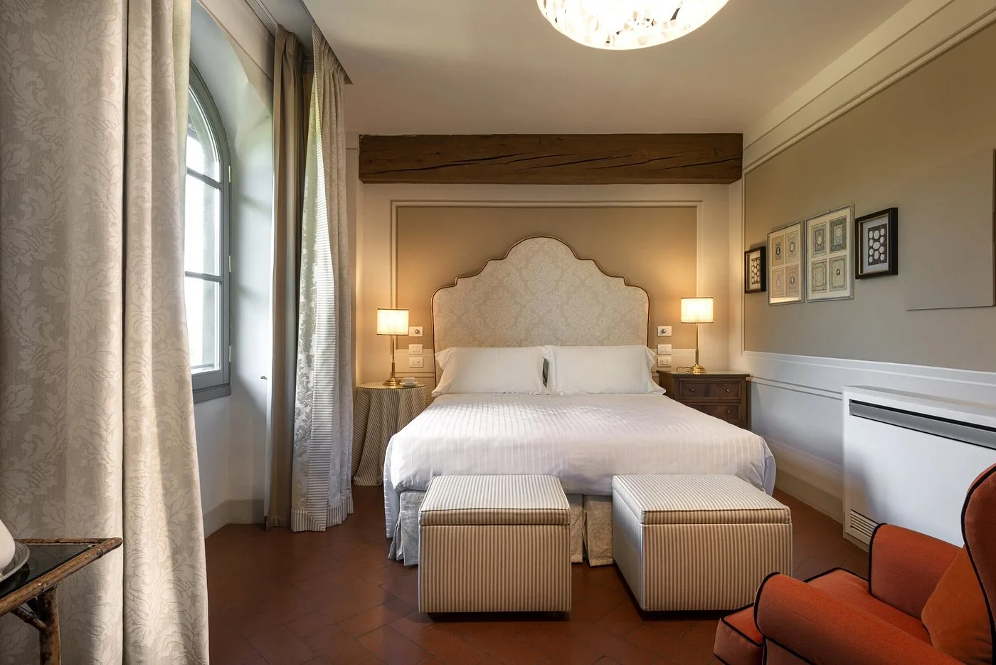Camera da letto elegante con testiera imbottita, finestra ad arco e pavimento in cotto