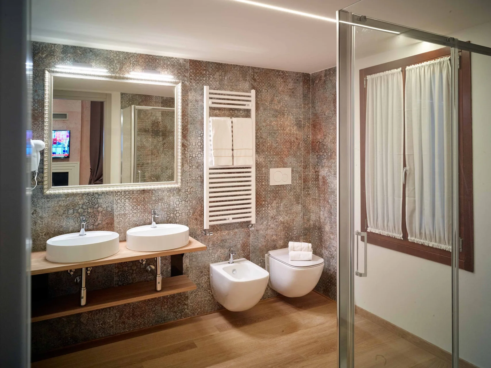 Bagno moderno con doppio lavabo, doccia, bidet e piastrelle decorate