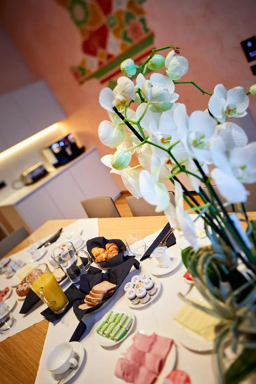 Tavolo della colazione con orchidea bianca, cornetti e affettati
