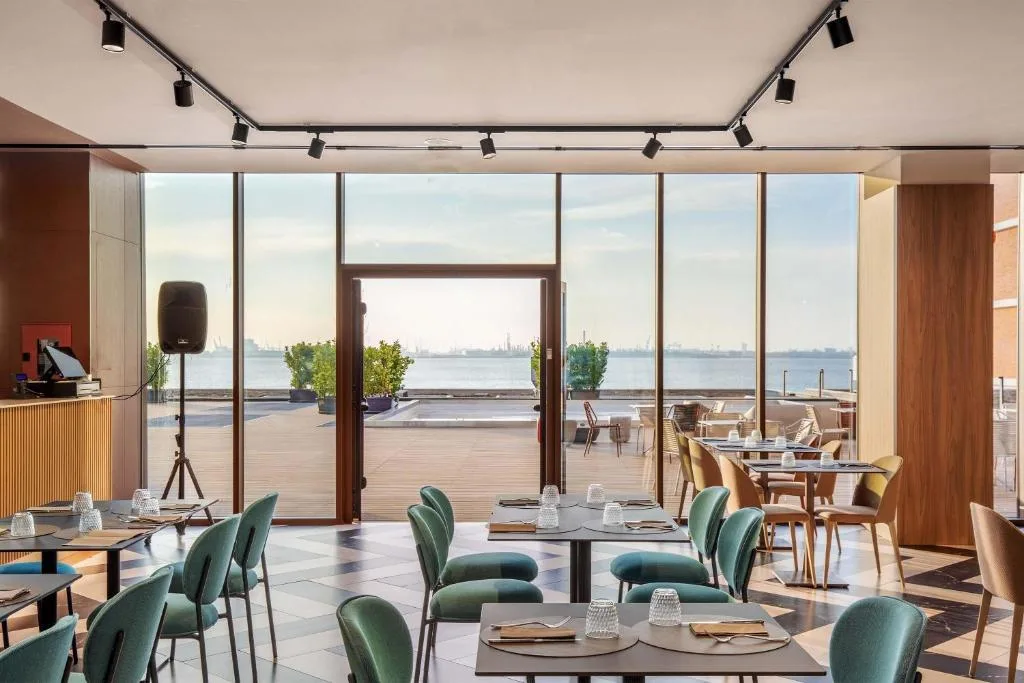 Sala ristorante con sedie verdi e vetrate affacciate sulla terrazza e il mare