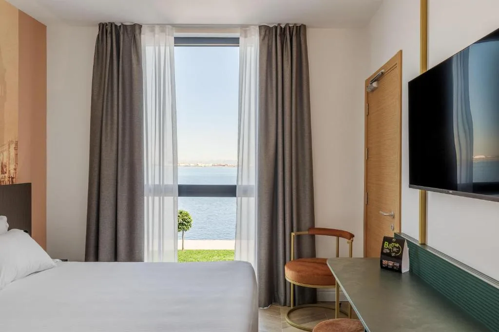 Camera con letto, TV e finestra affacciata sulla laguna