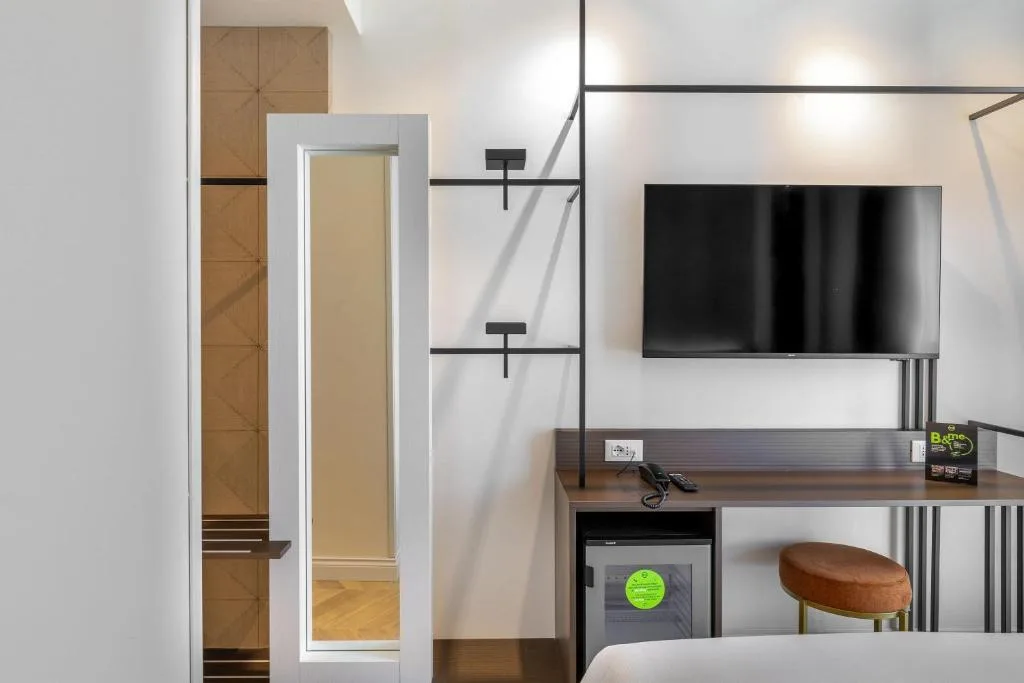 Dettaglio camera con TV a parete, scrivania e minibar