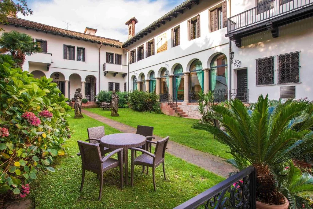 Cortile interno con giardino, statue, tavolo e sedie e architettura storica