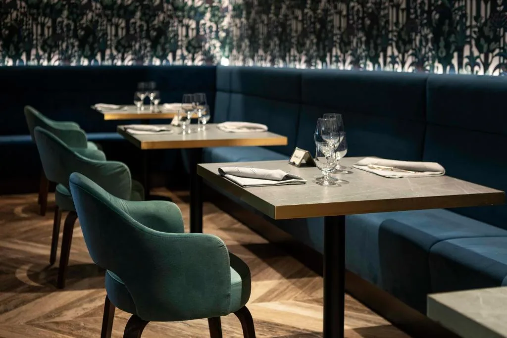 Ristorante elegante con sedie verdi, divanetti blu e pareti decorate