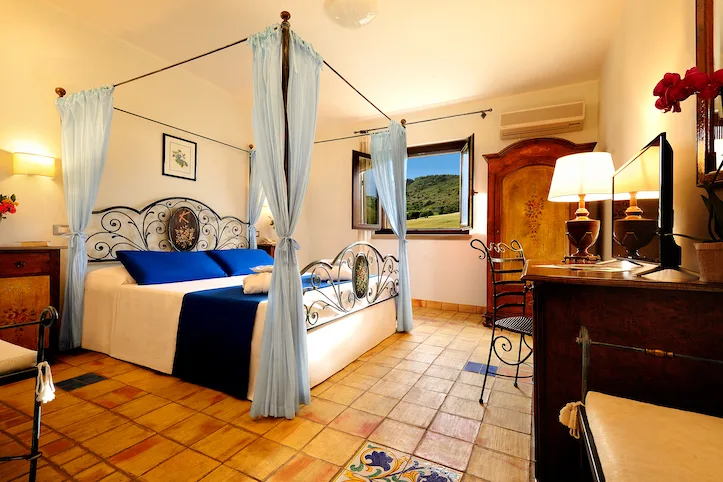 Camera elegante con letto a baldacchino in ferro battuto e vista collina