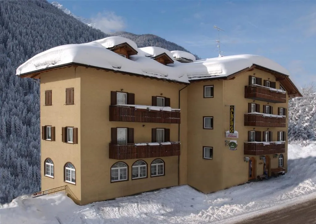 Facciata dell'Albergo Milano innevata in inverno con tetto coperto di neve e balconi in legno