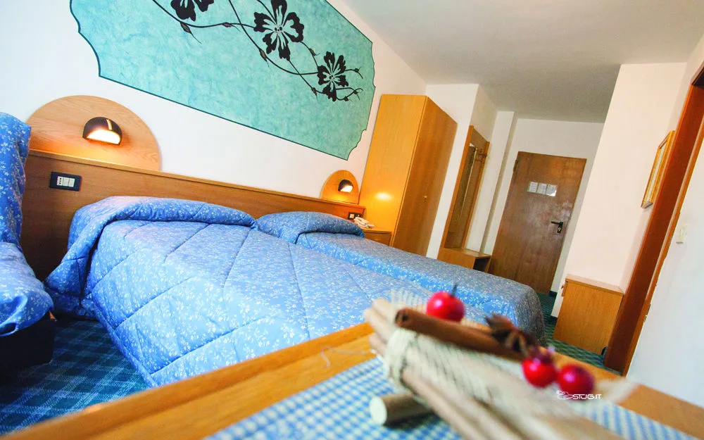 Camera con letto matrimoniale, decorazione floreale azzurra alla parete e moquette blu