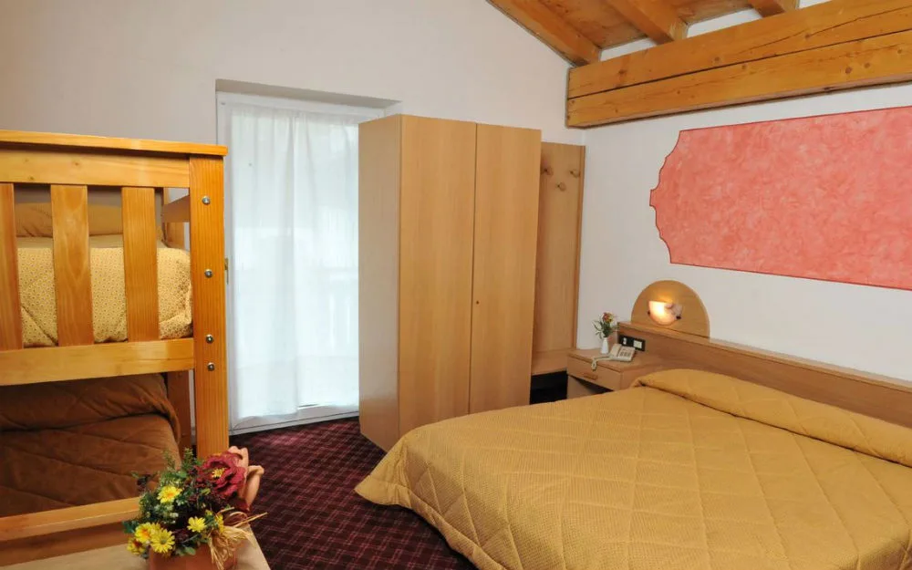 Camera da letto mansardata con letto matrimoniale, letto a castello e travi in legno a vista