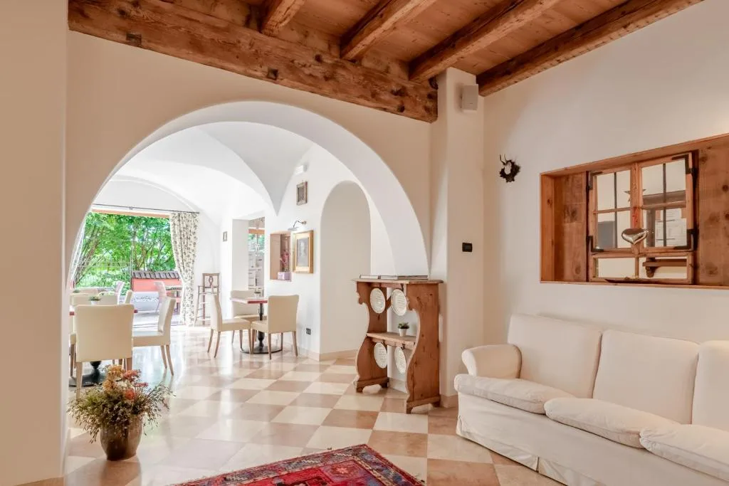 Sala con archi bianchi, divano bianco e pavimento a scacchi affacciata sulla sala colazione