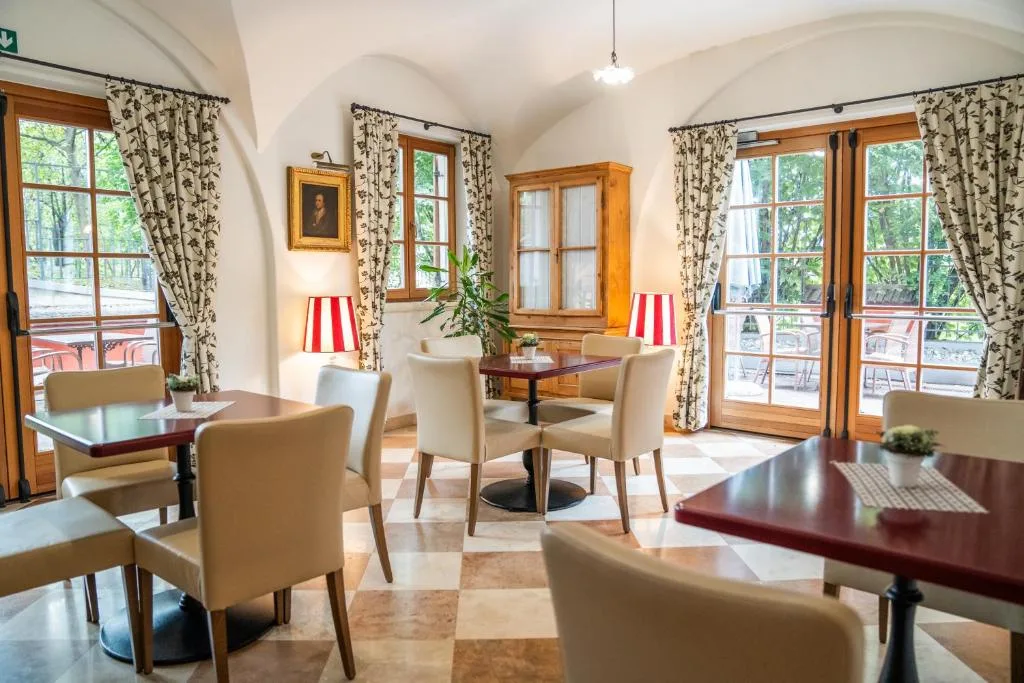 Sala colazione con volte a botte, tavoli rossi, sedie beige e tende floreali