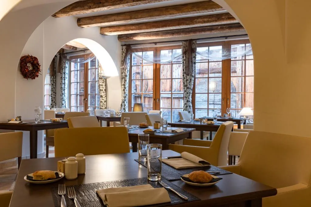 Sala colazione con travi a vista, tavoli apparecchiati e grandi finestre