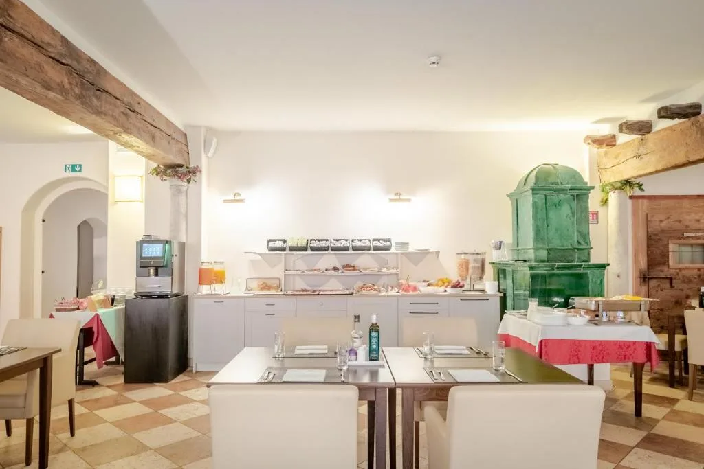 Sala colazione con buffet, stufa in maiolica verde e pavimento a scacchi