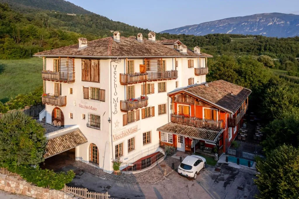 Veduta aerea del Relais Vecchio Maso con montagne e paese sullo sfondo