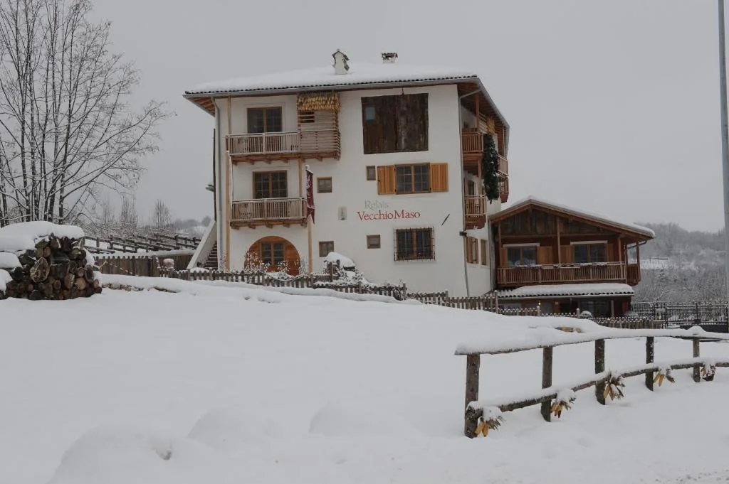 Facciata dell'hotel innevata in inverno con cataste di legna e balconi in legno