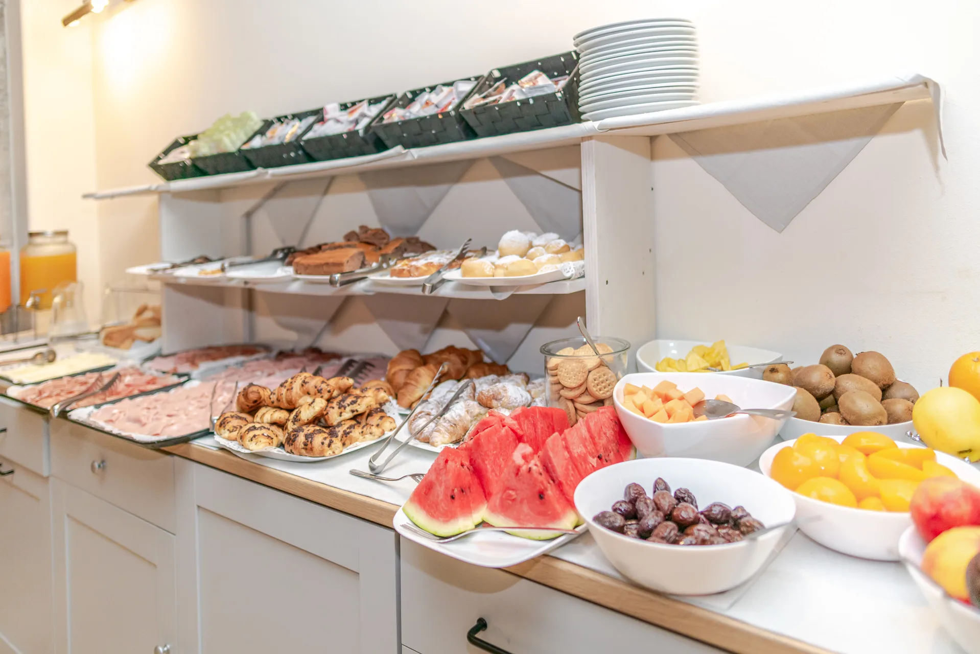 Buffet della colazione con affettati, cornetti, frutta fresca e anguria