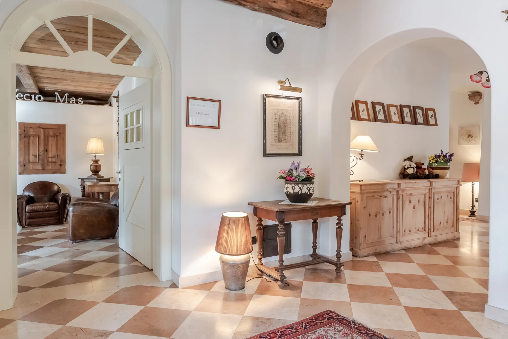 Ingresso interno con archi, pavimento a scacchi, mobili in legno e reception