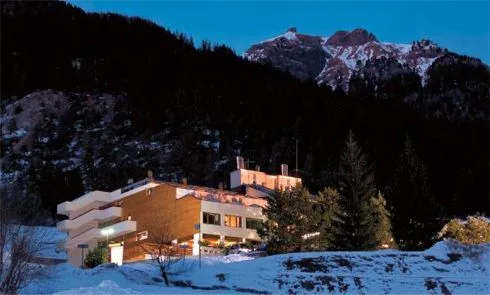 Vista notturna dell'hotel illuminato circondato dalla neve e dalle montagne