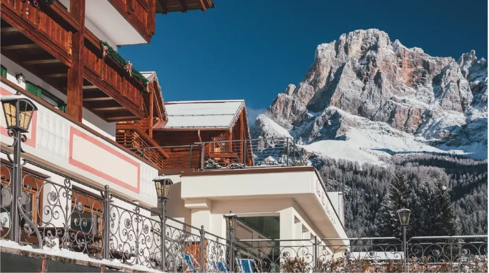 Balconi in legno dell'hotel con vista sulle cime rocciose innevate delle Dolomiti